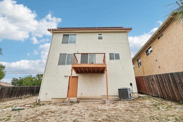 rear view of property featuring a fenced backyard, stucco siding, a balcony, and cooling unit