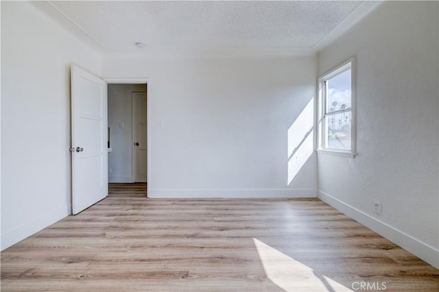 1144 W 57th St, Los Angeles, CA 90037 - spare room with baseboards, a textured ceiling, and light wood-style flooring