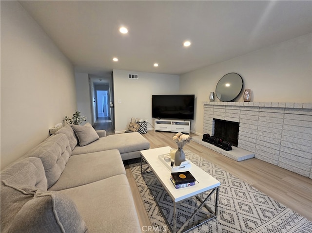 living room with a fireplace, recessed lighting, visible vents, and wood finished floors