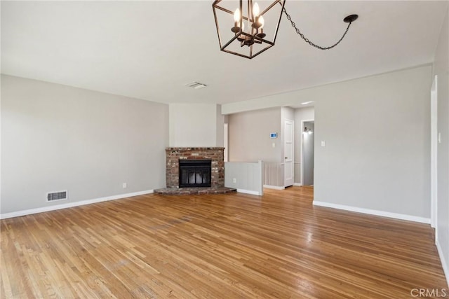 unfurnished living room with visible vents, light wood-style flooring, baseboards, and a fireplace