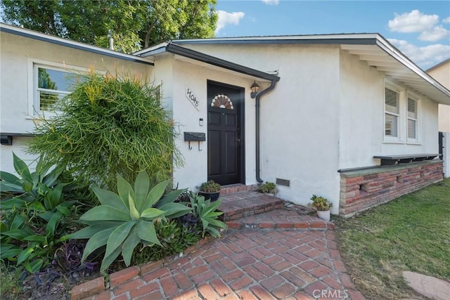 doorway to property with stucco siding and crawl space