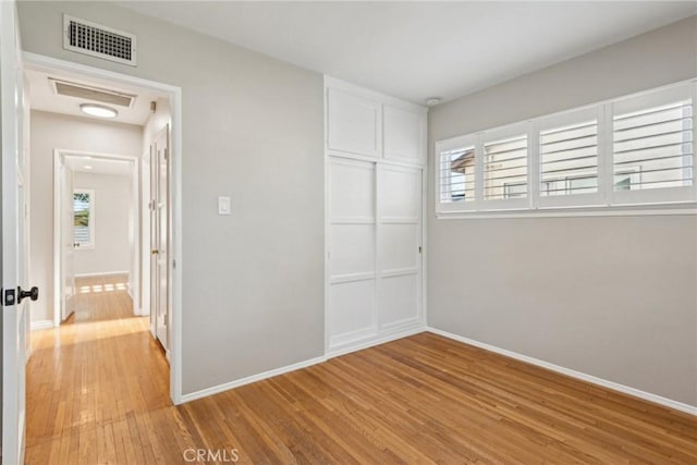 unfurnished bedroom featuring light wood-style floors, visible vents, baseboards, and a closet