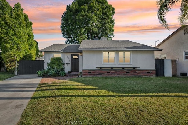 ranch-style house featuring fence, a gate, a yard, and driveway