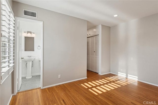 unfurnished bedroom with visible vents, baseboards, and wood finished floors