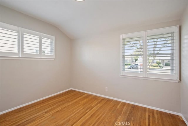 unfurnished room featuring plenty of natural light, light wood-style floors, lofted ceiling, and baseboards