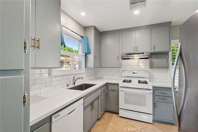 kitchen featuring a sink, gray cabinets, and white appliances