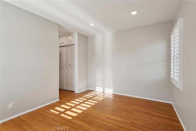 spare room featuring recessed lighting, baseboards, and wood finished floors