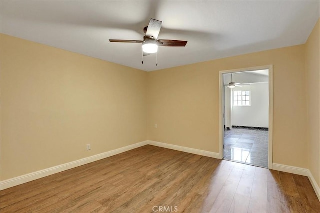 empty room with light wood-style floors, baseboards, and ceiling fan