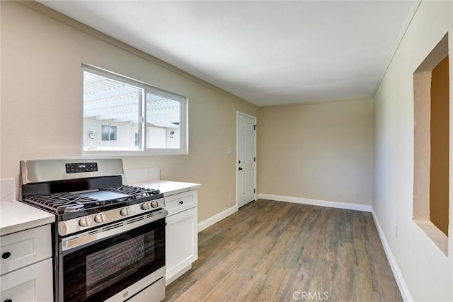 kitchen with light countertops, light wood-type flooring, stainless steel range with gas cooktop, and white cabinetry
