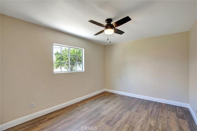 empty room featuring baseboards, a ceiling fan, and wood finished floors