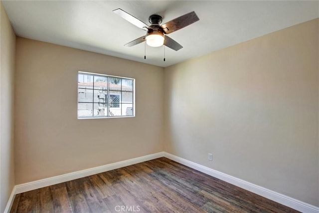empty room with baseboards, a ceiling fan, and dark wood-type flooring