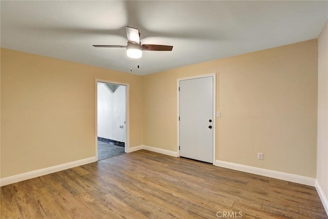 empty room with baseboards, ceiling fan, and wood finished floors