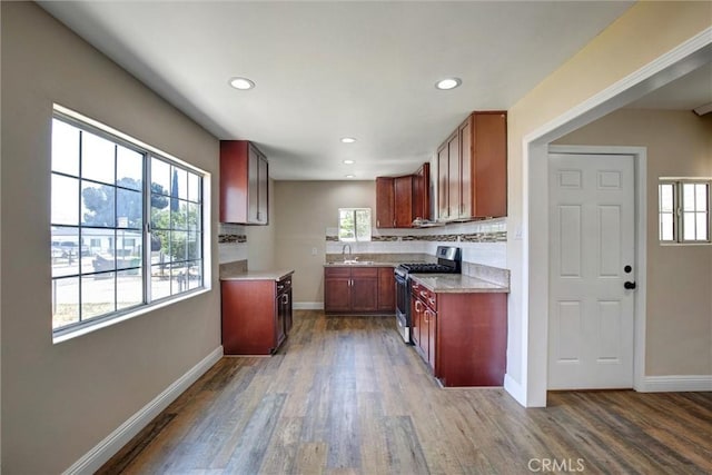 kitchen with wood finished floors, baseboards, recessed lighting, stainless steel range with gas stovetop, and a sink