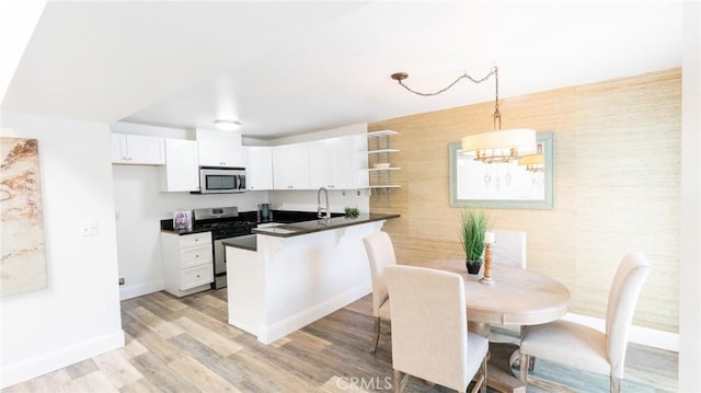 kitchen featuring dark countertops, appliances with stainless steel finishes, open shelves, a chandelier, and baseboards