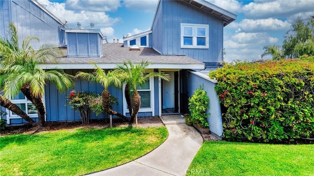 view of front of property with a shingled roof and a front lawn