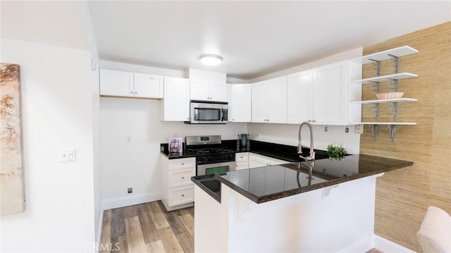 kitchen featuring appliances with stainless steel finishes, white cabinets, open shelves, and a peninsula
