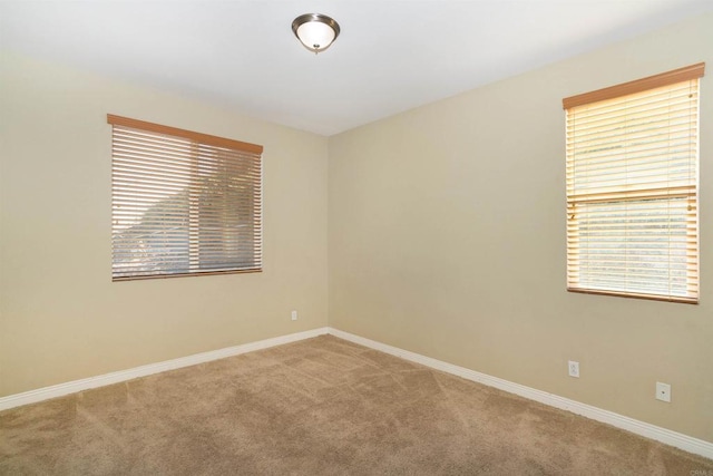 carpeted spare room with baseboards and a healthy amount of sunlight