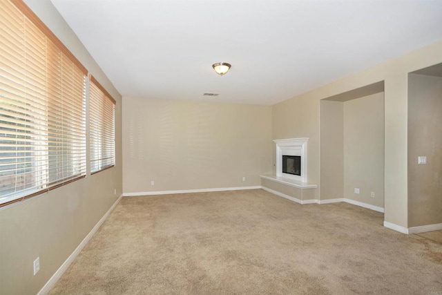 unfurnished living room featuring baseboards, visible vents, and light colored carpet