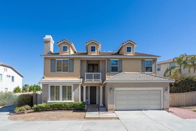 traditional-style home featuring fence, stucco siding, a chimney, a balcony, and driveway