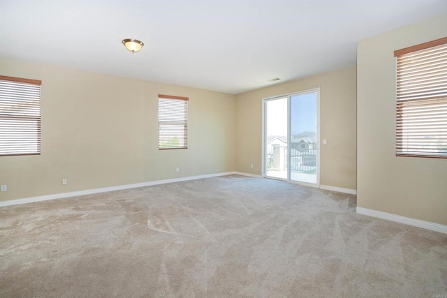 empty room featuring light colored carpet and baseboards
