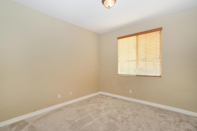 empty room featuring baseboards and light carpet