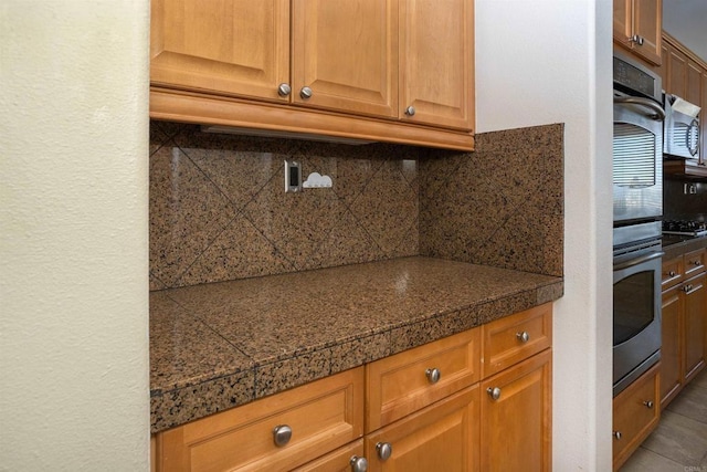 kitchen with brown cabinets, tile countertops, decorative backsplash, and stainless steel appliances