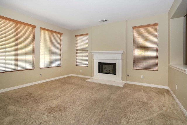 unfurnished living room with visible vents, a fireplace with raised hearth, baseboards, and light carpet