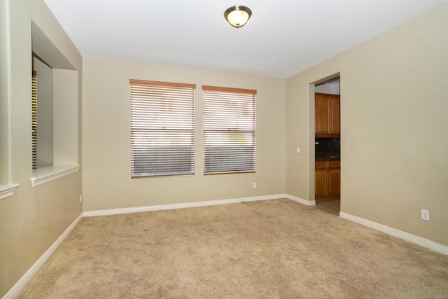 spare room featuring baseboards and light carpet