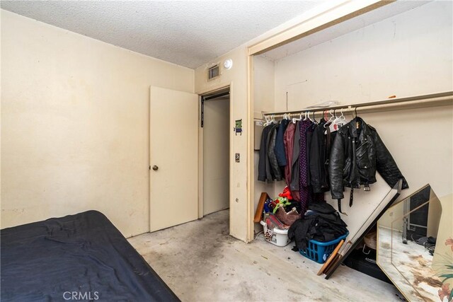 bedroom featuring unfinished concrete floors and a textured ceiling