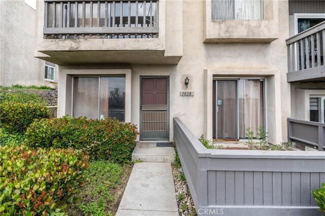 property entrance featuring a balcony and stucco siding