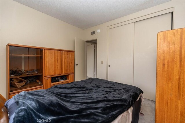 bedroom with light carpet, a closet, and a textured ceiling