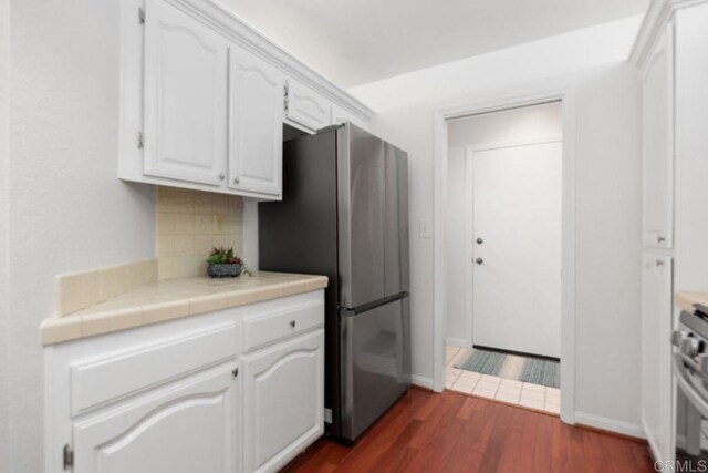 814 Okra Ct, Carlsbad, CA 92011 - kitchen with freestanding refrigerator, white cabinetry, dark wood-style floors, backsplash, and range