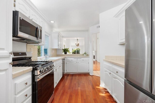 814 Okra Ct, Carlsbad, CA 92011 - kitchen with appliances with stainless steel finishes, tile countertops, white cabinets, decorative backsplash, and recessed lighting