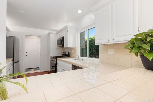 814 Okra Ct, Carlsbad, CA 92011 - kitchen with stainless steel appliances, white cabinets, decorative backsplash, tile counters, and recessed lighting