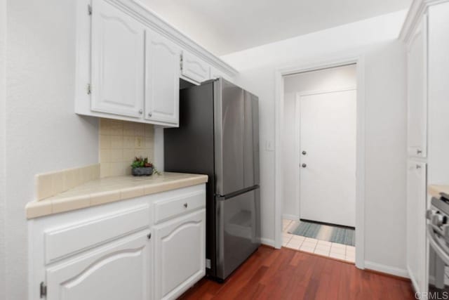 814 Okra Ct, Carlsbad, CA 92011 - kitchen with freestanding refrigerator, white cabinetry, dark wood-type flooring, tasteful backsplash, and stove