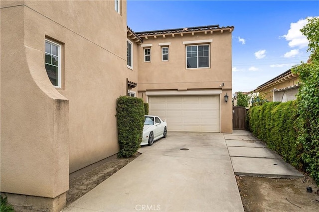 2677 E Tyler St, Long Beach, CA 90810 - view of side of home with an attached garage, stucco siding, and driveway