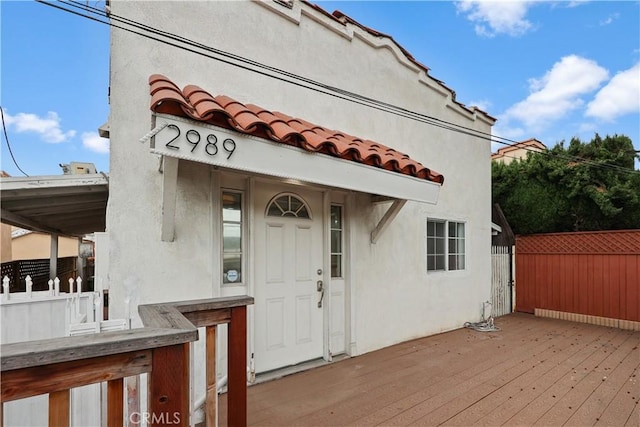2989 W 12th St, Los Angeles, CA 90006 - entrance to property featuring fence, a wooden deck, a tiled roof, and stucco siding