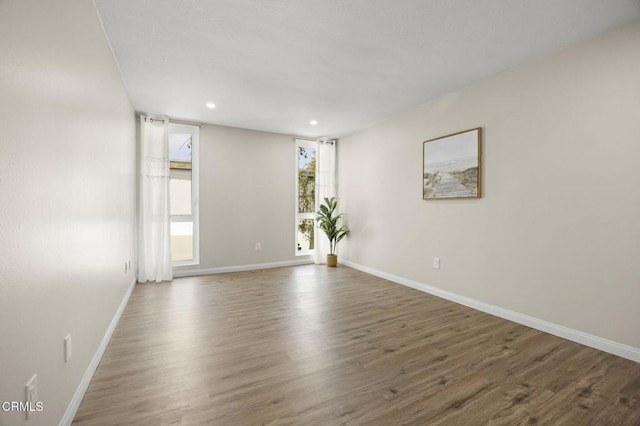 spare room featuring baseboards, recessed lighting, and wood finished floors