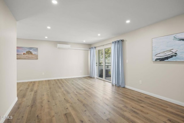 unfurnished room featuring baseboards, recessed lighting, a wall unit AC, and wood finished floors