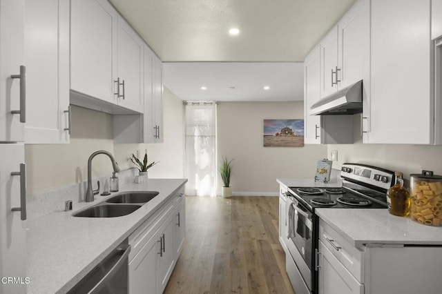 kitchen with a sink, baseboards, white cabinets, under cabinet range hood, and stainless steel appliances
