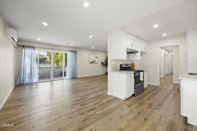 kitchen featuring light wood-style floors, an AC wall unit, light countertops, under cabinet range hood, and stainless steel electric stove