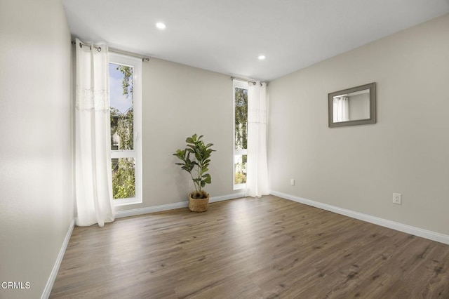 spare room with recessed lighting, baseboards, and wood finished floors