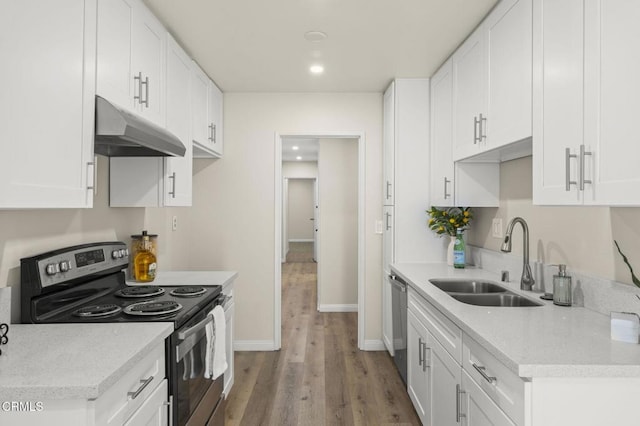 kitchen with wood finished floors, white cabinetry, under cabinet range hood, a sink, and appliances with stainless steel finishes