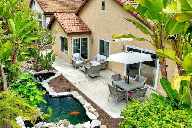 rear view of house with an outdoor hangout area, stucco siding, a small pond, a patio area, and a tiled roof