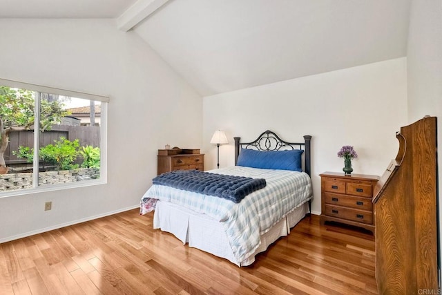 bedroom with baseboards, lofted ceiling with beams, and wood finished floors