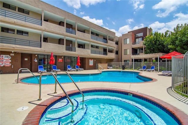 community pool with fence, a community hot tub, and a patio area
