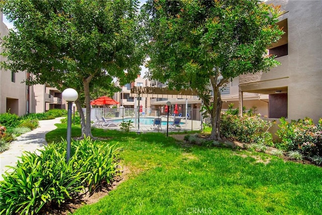 view of property's community with a yard, a swimming pool, and fence