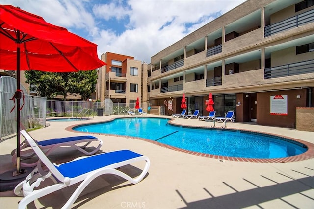 community pool with a patio area and fence