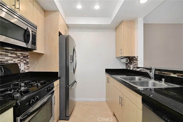 kitchen with stainless steel appliances, light tile patterned flooring, a sink, and light brown cabinets