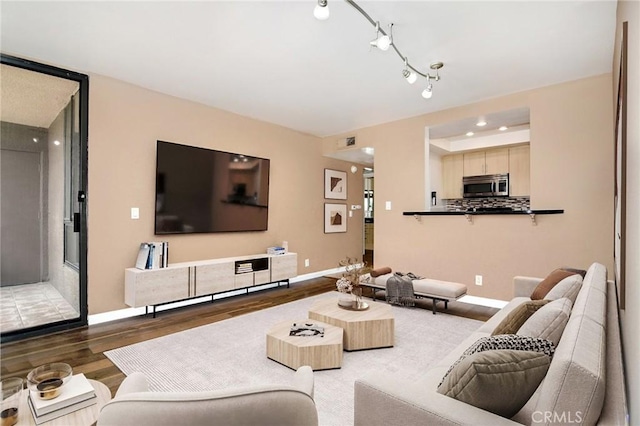 living area with baseboards, wood finished floors, and visible vents